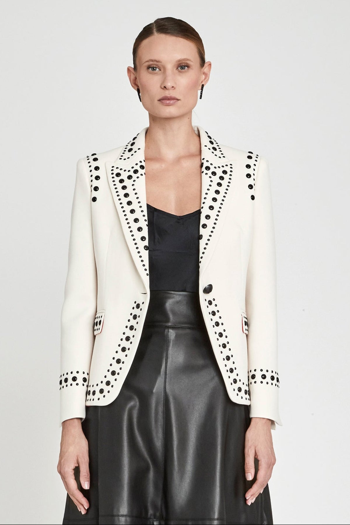 Blazer blanco roto con tachuelas Rock Star entallada con solapa de punta de lanza y tachas negras de alto brillo. Sastrería artesanal hecha en España.
