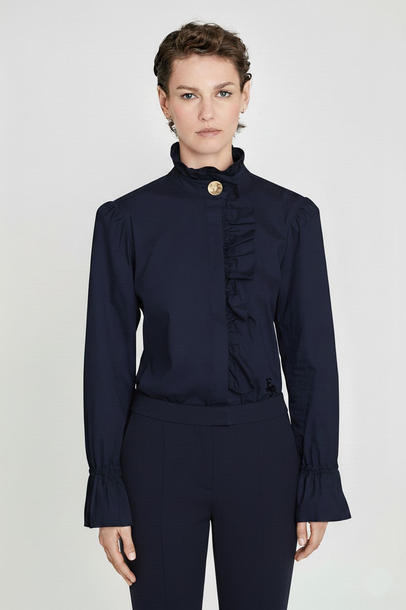 Camisa marino Boheme con cuello alto fruncido, volantes en botonadura central y mangas acampanadas. Elegancia y romanticismo.