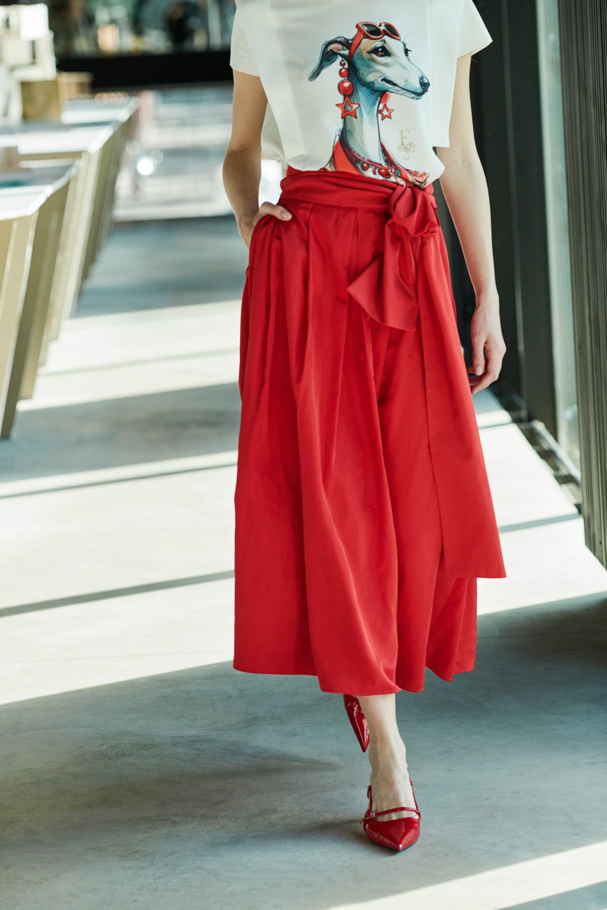 Falda midi roja estructurada con volumen teatral, corte evasé y gran lazo sastre lateral. Alta costura, exclusividad y diseño artesanal hecho en España.