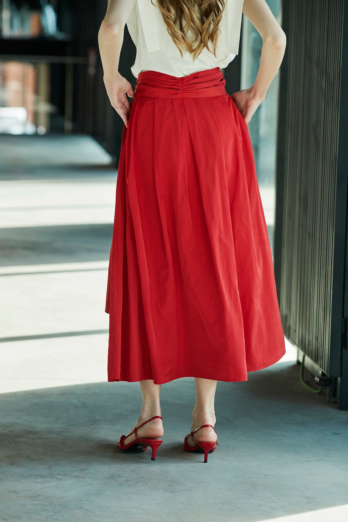 Falda midi roja estructurada con volumen teatral, corte evasé y gran lazo sastre lateral. Alta costura, exclusividad y diseño artesanal hecho en España.