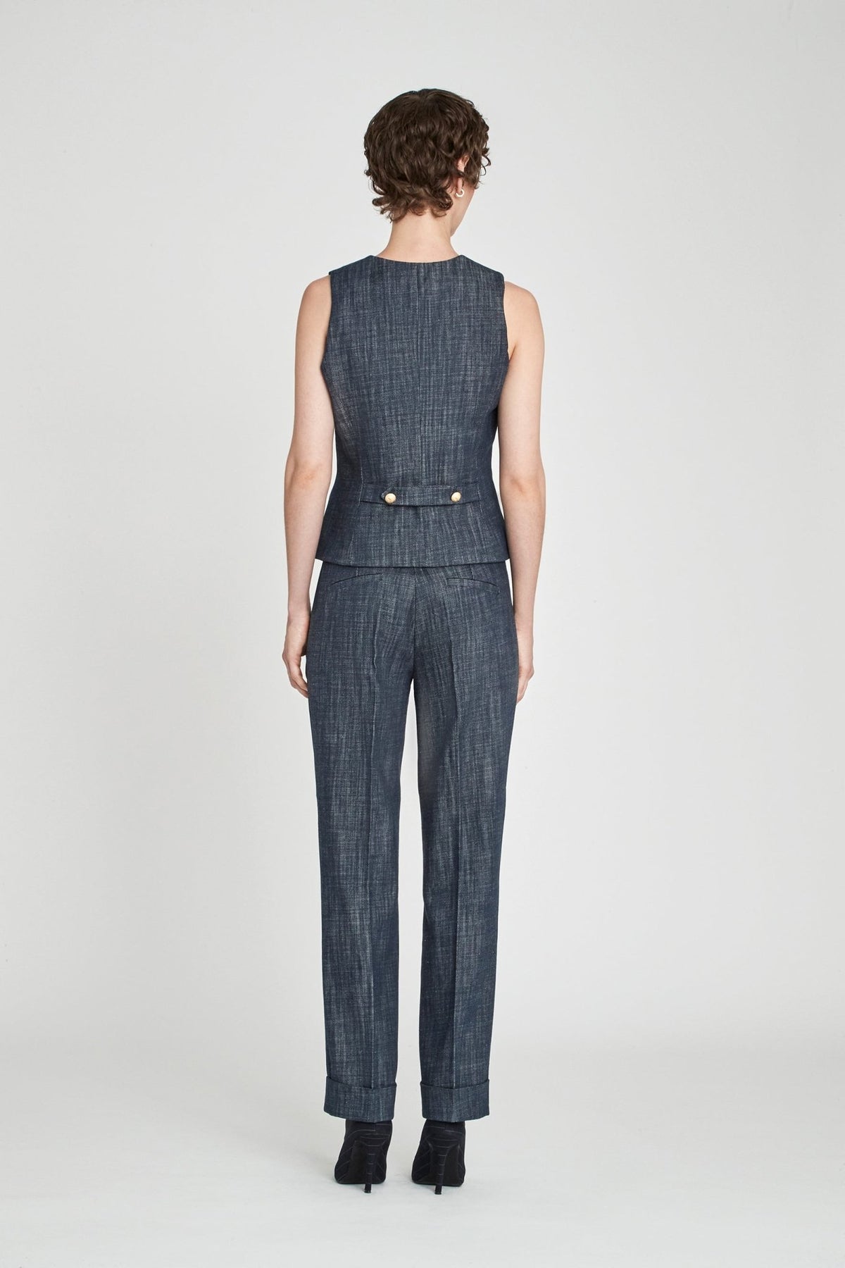 Chaleco sastre denim Milán entallado en azul de alta calidad con escote en V, botones dorados y detalles artesanales. Sofisticación moderna y versátil.