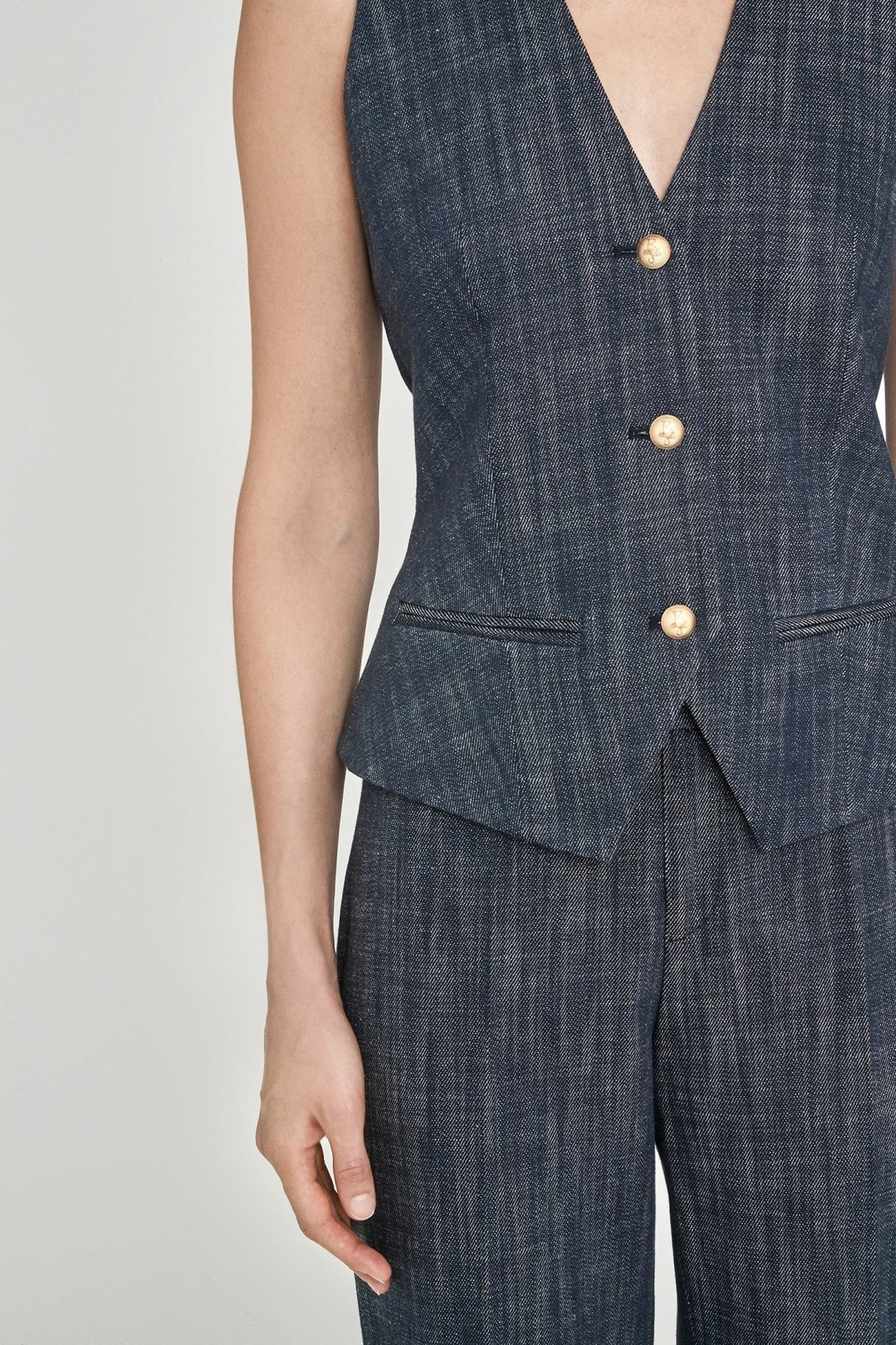 Chaleco sastre denim Milán entallado en azul de alta calidad con escote en V, botones dorados y detalles artesanales. Sofisticación moderna y versátil.