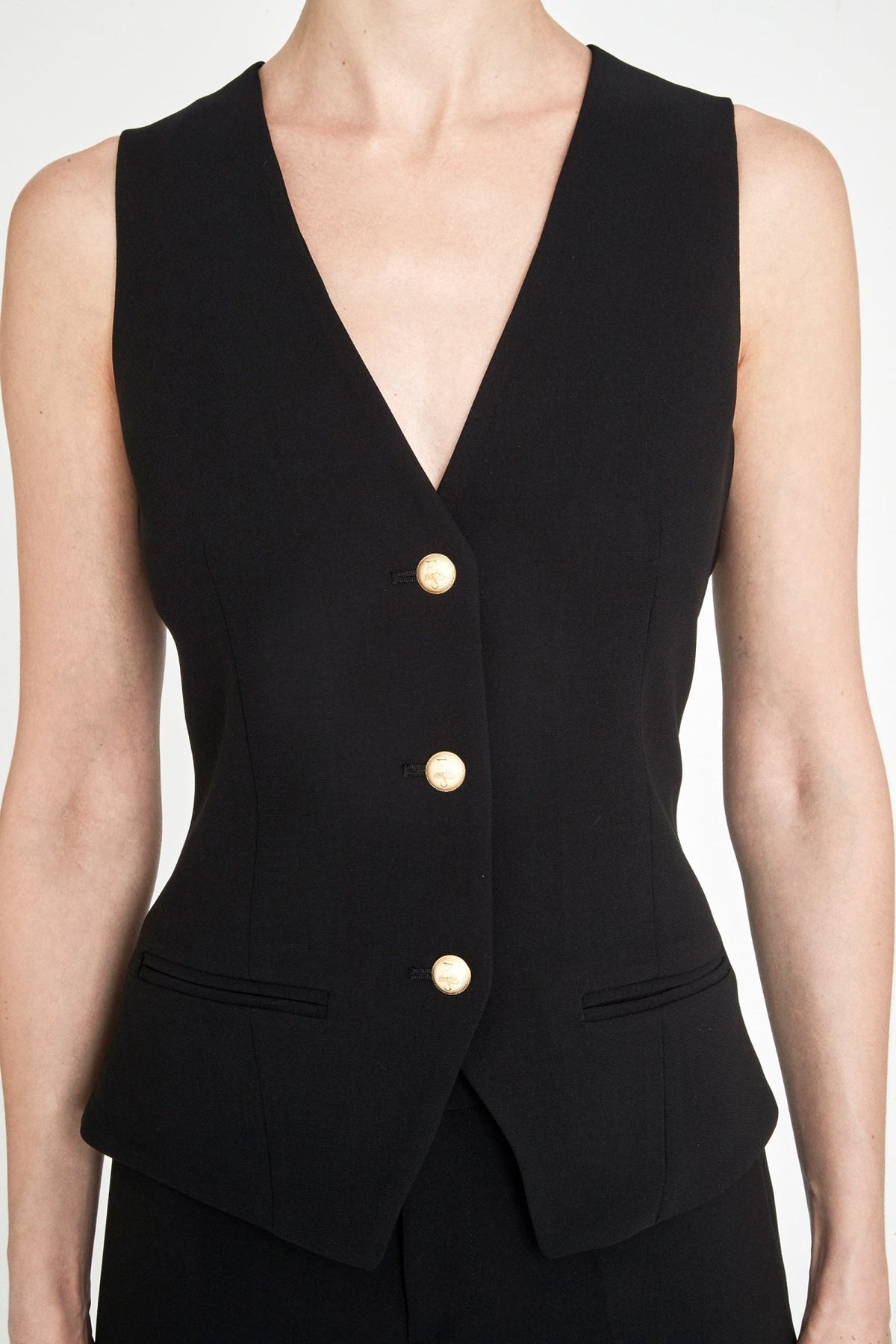 Chaleco sastre negro Atelier en super crepé de tres botones con bolsillos de vivo y detalles dorados con logo.