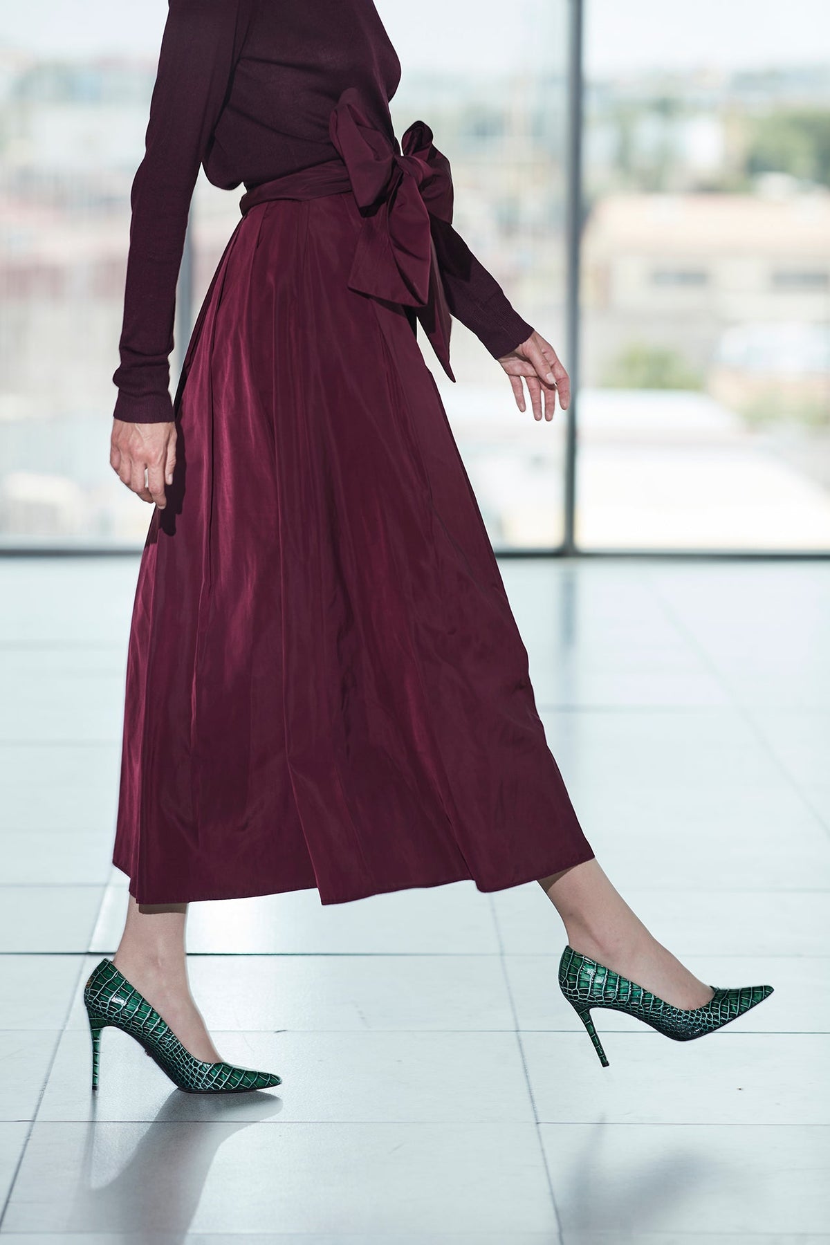 Falda midi granate estructurada con volumen teatral, corte evasé y gran lazo sastre lateral. Alta costura, exclusividad y diseño artesanal hecho en España.