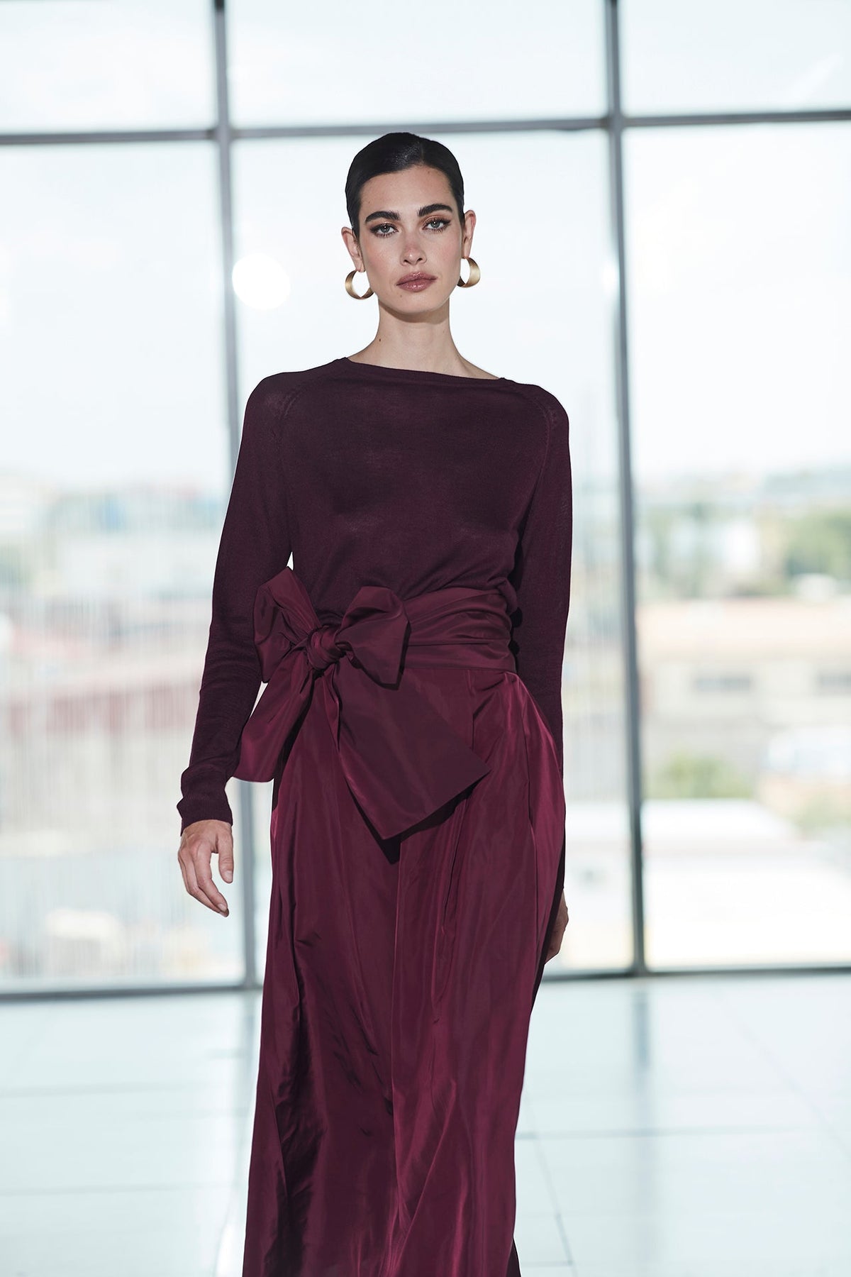 Falda midi granate estructurada con volumen teatral, corte evasé y gran lazo sastre lateral. Alta costura, exclusividad y diseño artesanal hecho en España.