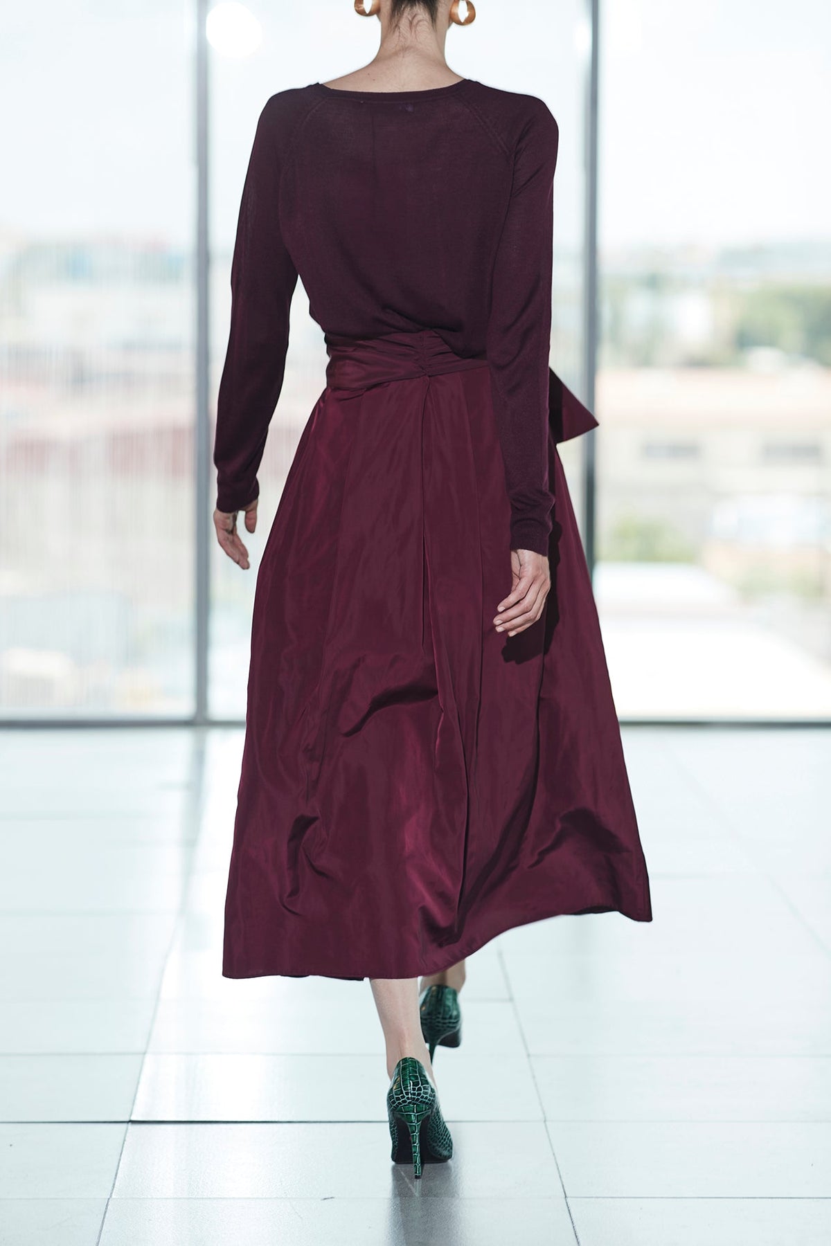 Falda midi granate estructurada con volumen teatral, corte evasé y gran lazo sastre lateral. Alta costura, exclusividad y diseño artesanal hecho en España.
