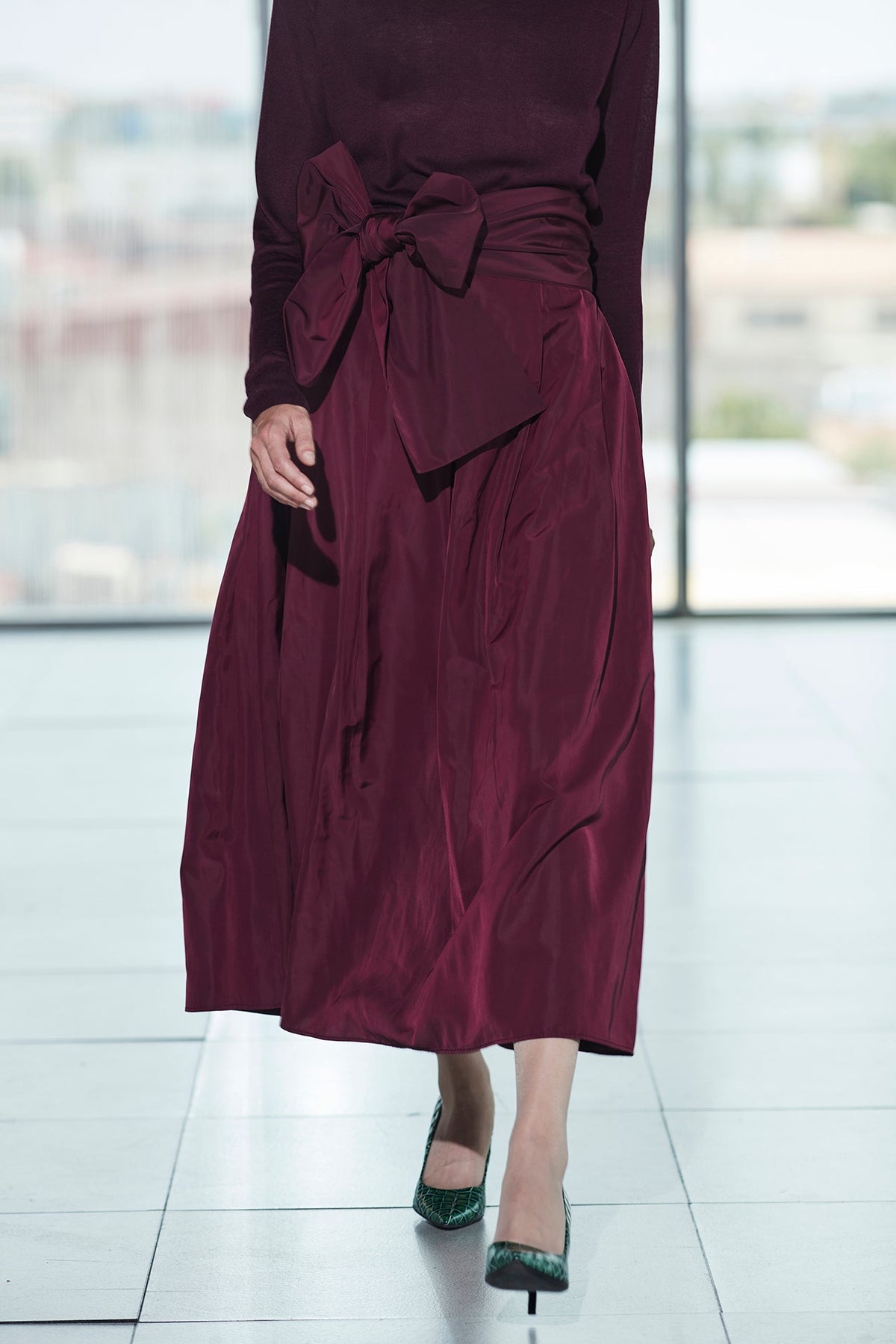 Falda midi granate estructurada con volumen teatral, corte evasé y gran lazo sastre lateral. Alta costura, exclusividad y diseño artesanal hecho en España.