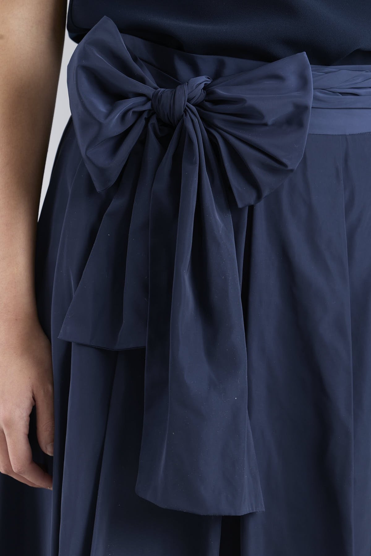 Falda midi marino estructuradacon volumen impecable, corte evasé y gran lazo sastre lateral. Alta costura, exclusividad y diseño artesanal hecho en España.