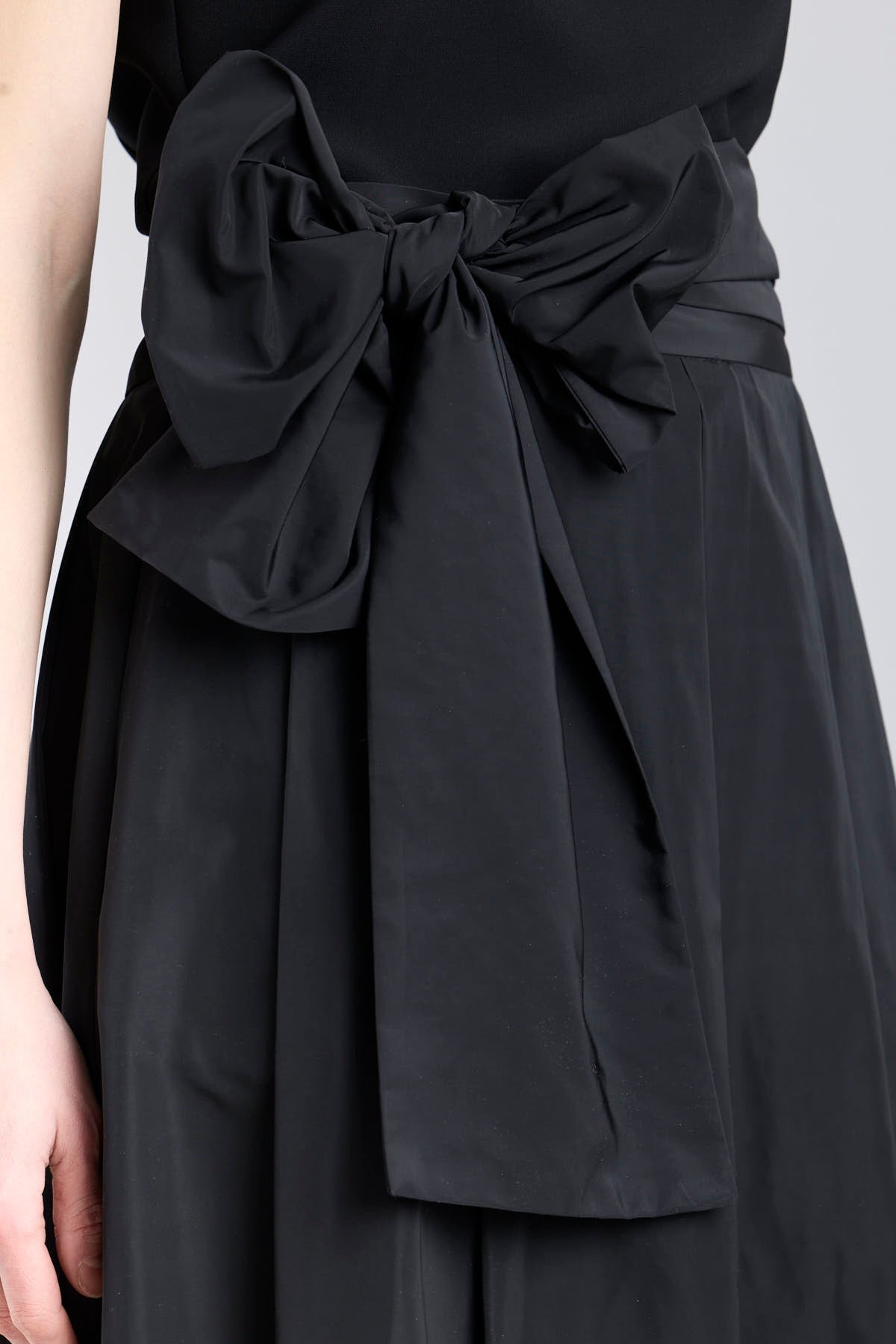 Falda midi negro estructurada con volumen teatral, corte evasé y gran lazo sastre lateral. Alta costura, exclusividad y diseño artesanal hecho en España.