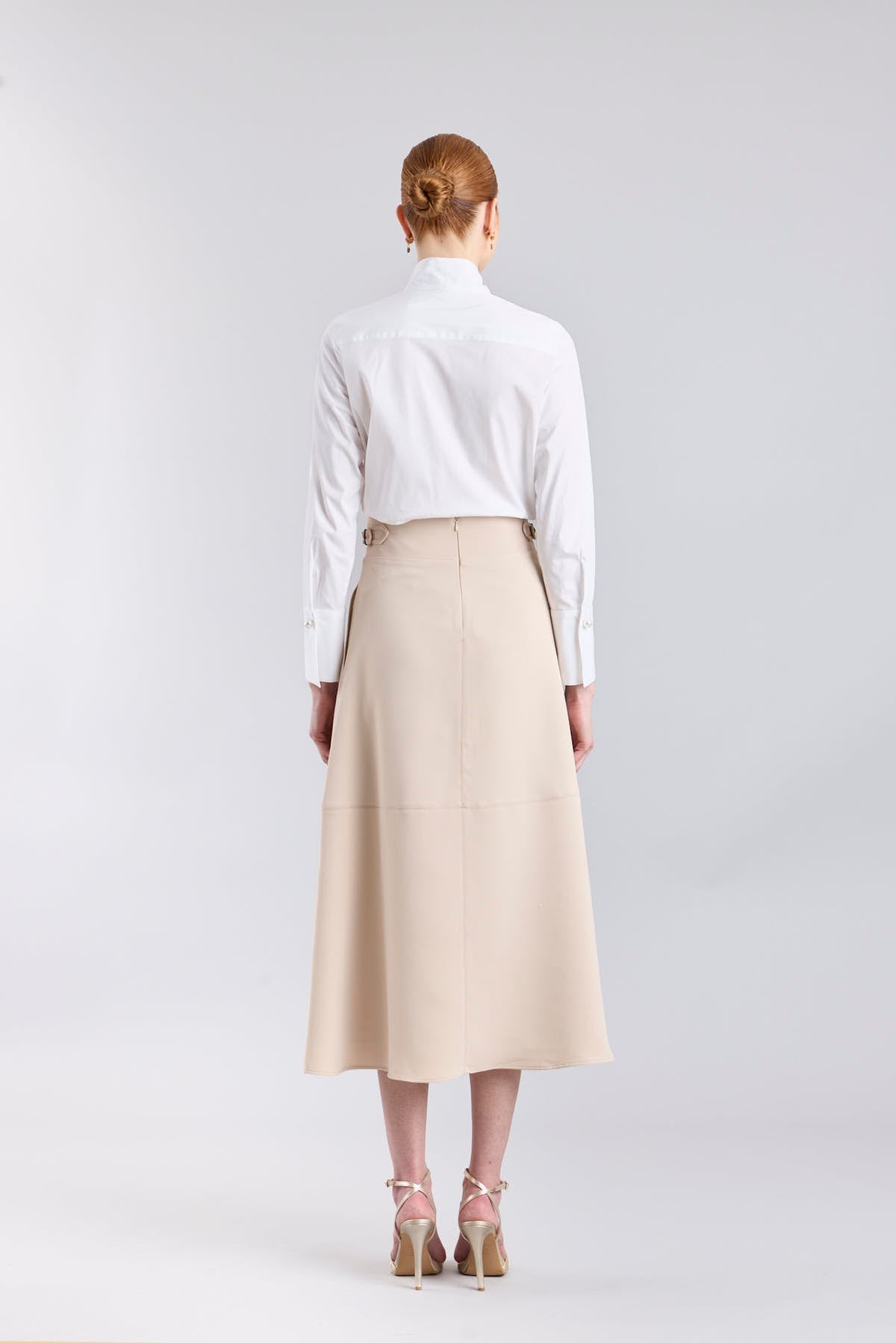 Falda midi de corte evasé color beige con detalle de hebillas en la cintura de The Extreme Collection.
