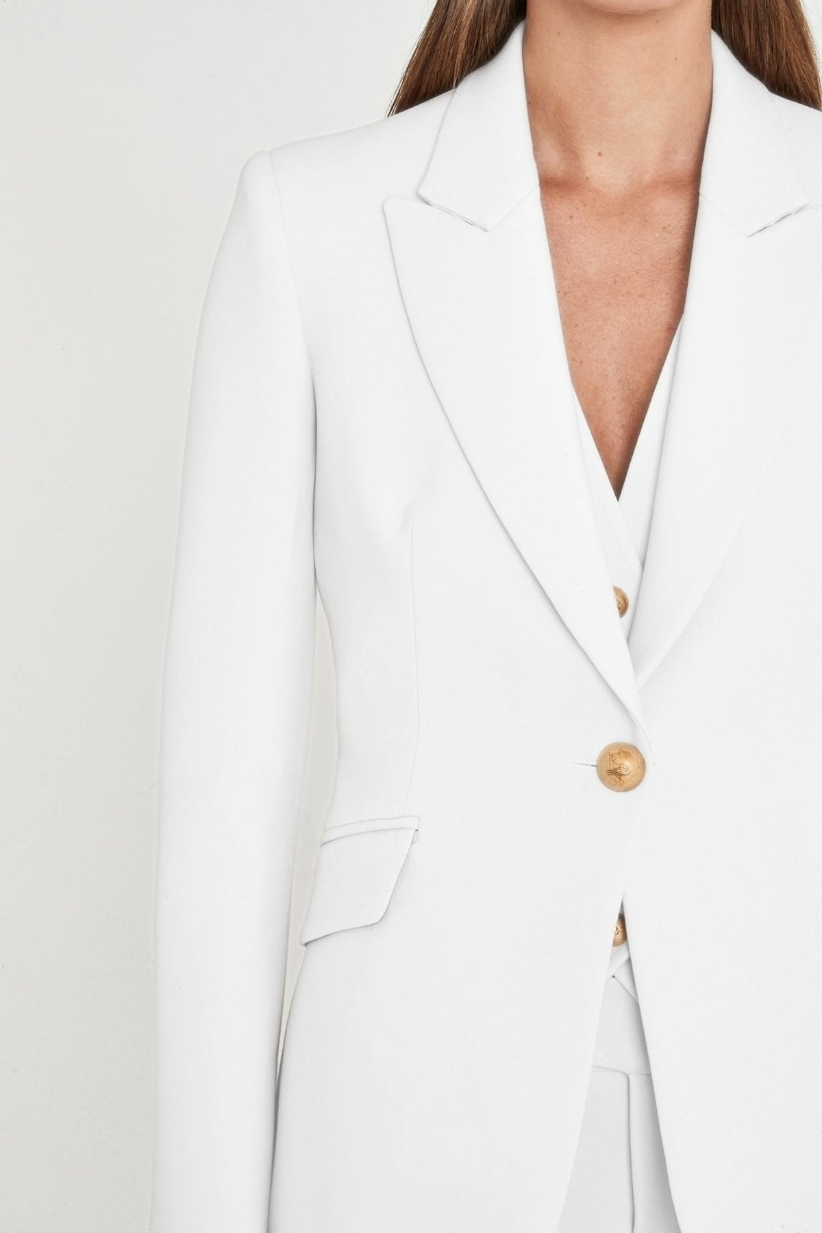 Blazer entallada blanca Paris de super crepe con solapa de pico, botón metálico dorado y bolsillos de cartera. Elegancia artesanal y sostenible.