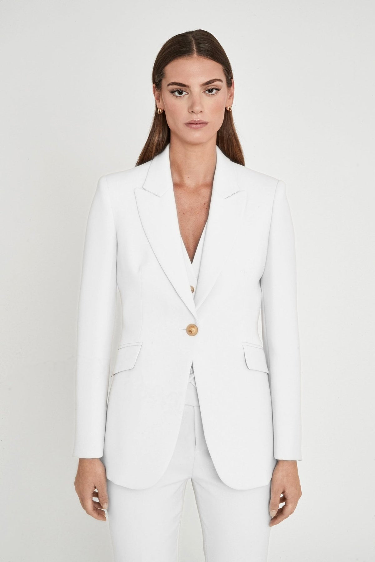 Blazer entallada blanca Paris de super crepe con solapa de pico, botón metálico dorado y bolsillos de cartera. Elegancia artesanal y sostenible.