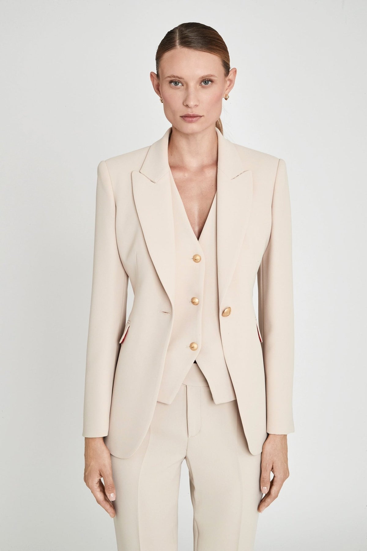Blazer entallada beige Paris de tejido liso en tono tofe con solapa clásica, botón dorado central y estructura impecable.