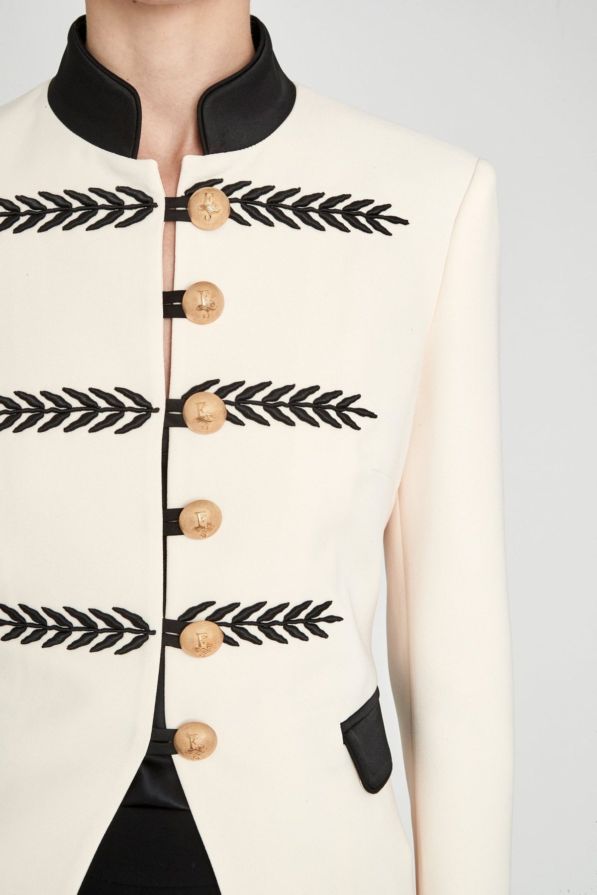 Blazer militar marfil Renata 01 corta y entallada en tejido color crema con cuello mao negro, bordados geométricos y botones dorados. Sastrería de lujo.