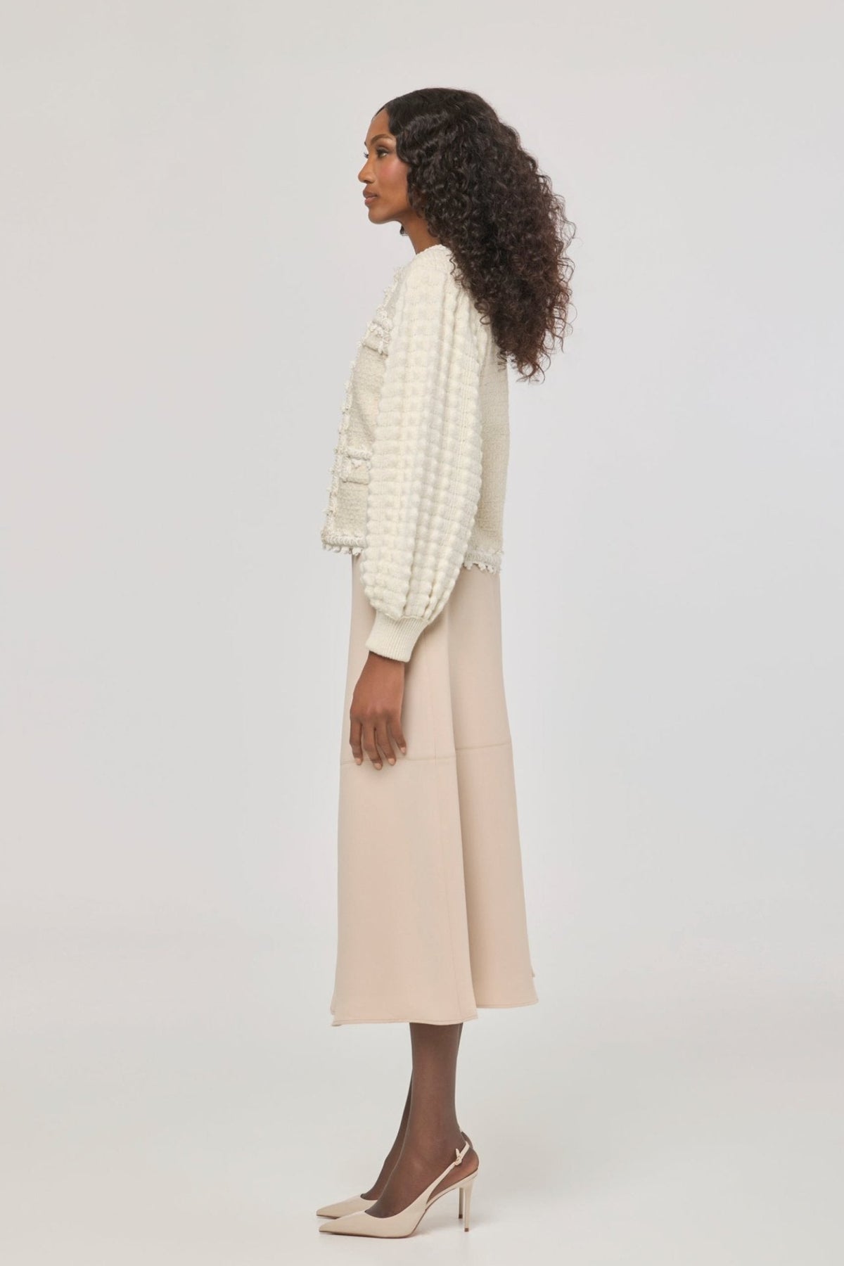 Cárdigan corto blanco de punto para mujer con estética estilo tweed, mangas abullonadas y ribetes detallados.