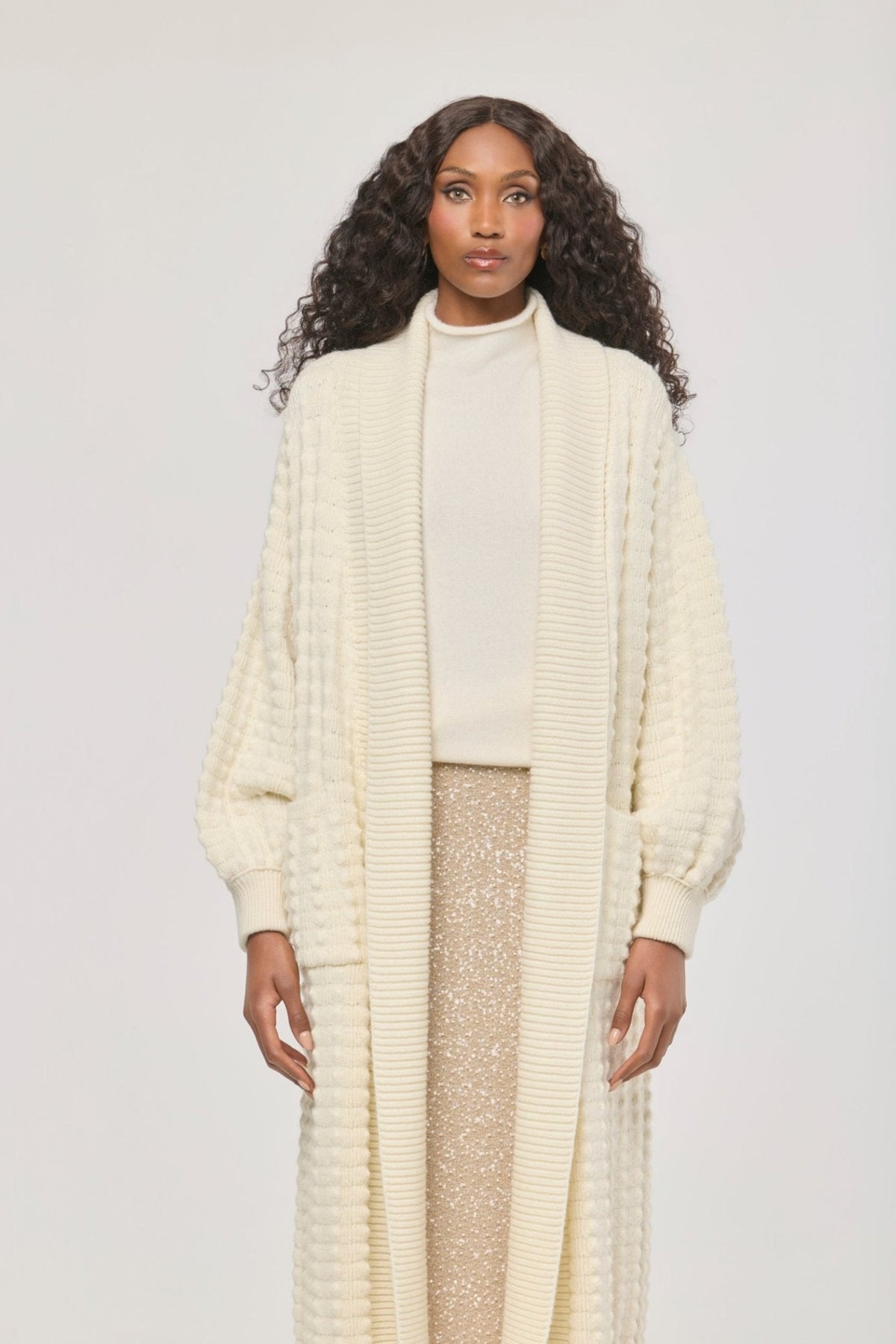 Cárdigan largo de punto blanco blanco para mujer con mangas de textura geométrica y diseño minimalista.