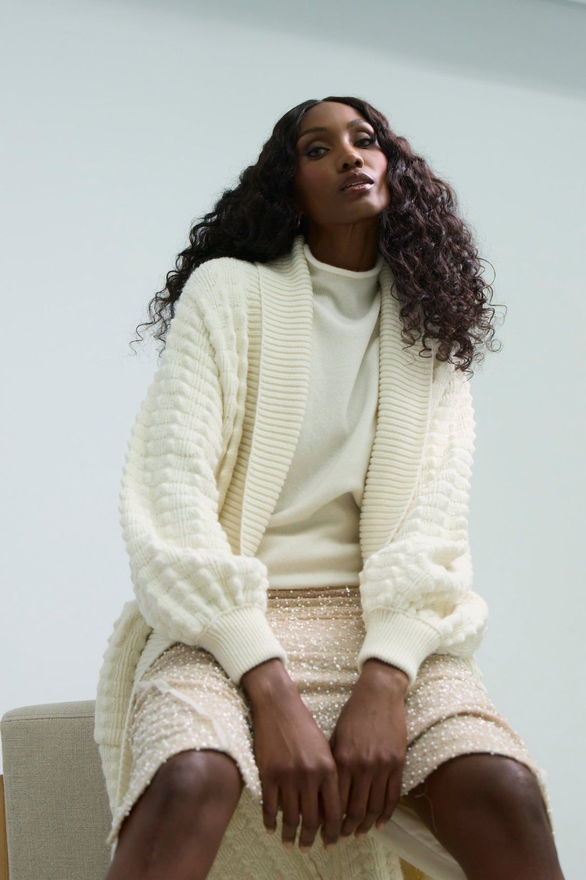 Cárdigan largo de punto blanco blanco para mujer con mangas de textura geométrica y diseño minimalista.