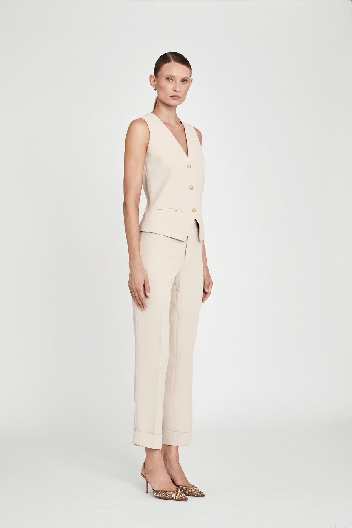 Chaleco sastre beige Atelier en crepe liso en tono tofe con escote en V, tres botones dorados y silueta entallada. Sastrería elegante y sofisticada.