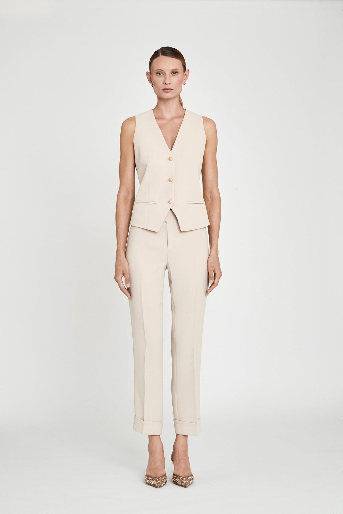 Chaleco sastre beige Atelier en crepe liso en tono tofe con escote en V, tres botones dorados y silueta entallada. Sastrería elegante y sofisticada.