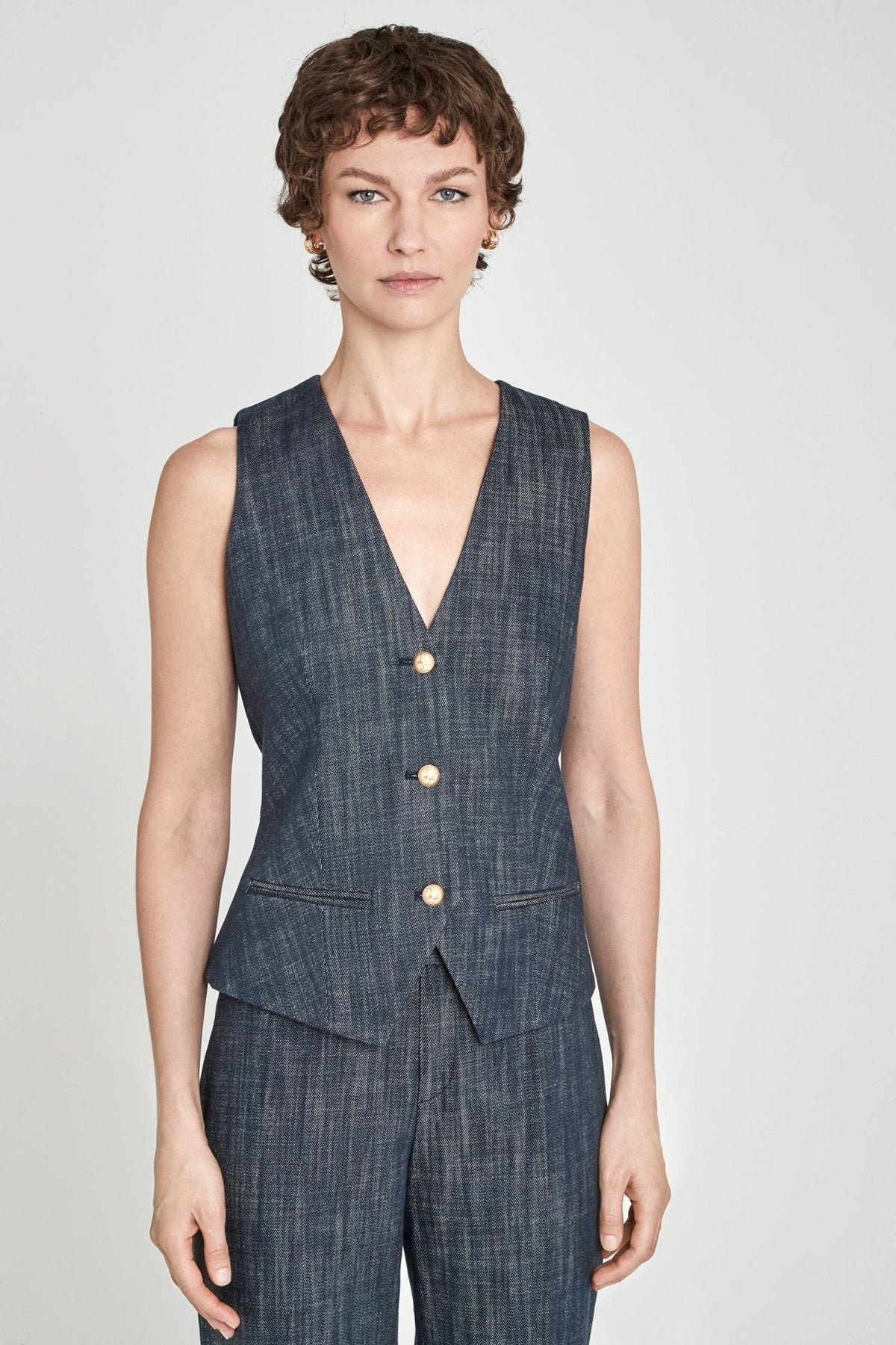 Chaleco sastre denim Milán entallado en azul de alta calidad con escote en V, botones dorados y detalles artesanales. Sofisticación moderna y versátil.