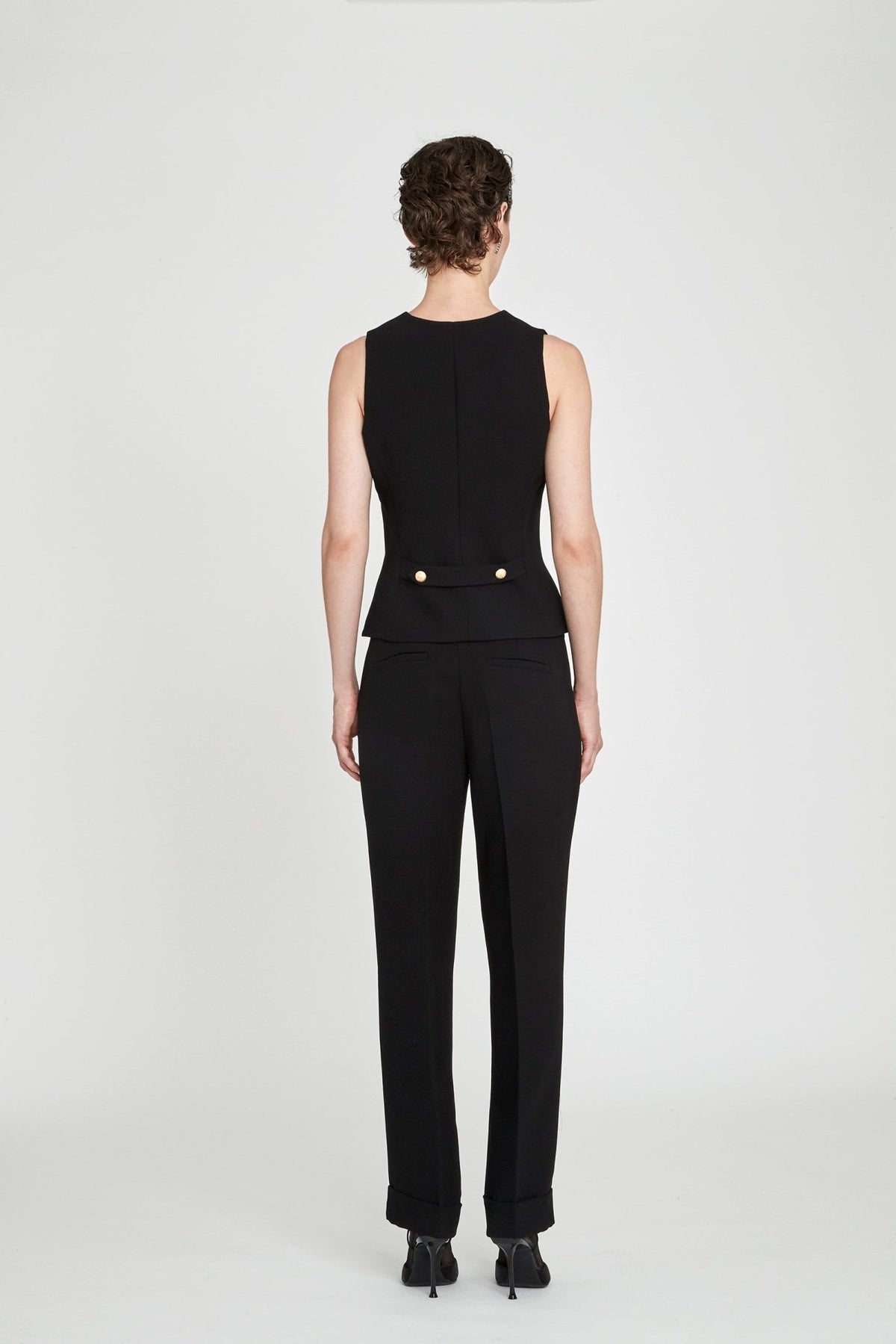 Chaleco sastre negro Atelier en super crepé de tres botones con bolsillos de vivo y detalles dorados con logo.