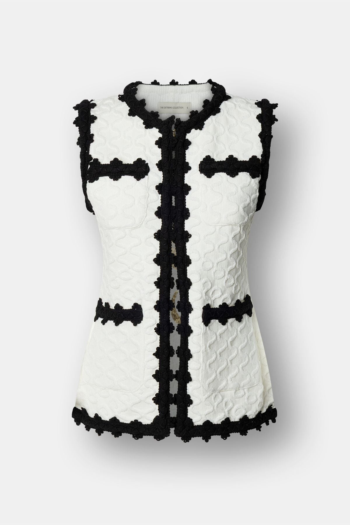 Chaleco de lujo blanco para mujer modelo Tristan con perfiles festoneados en negro.